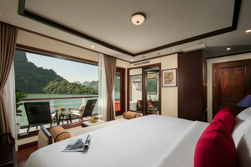 A balcony cabin on a BAT Group ship with a large bed facing a wide window over the bay